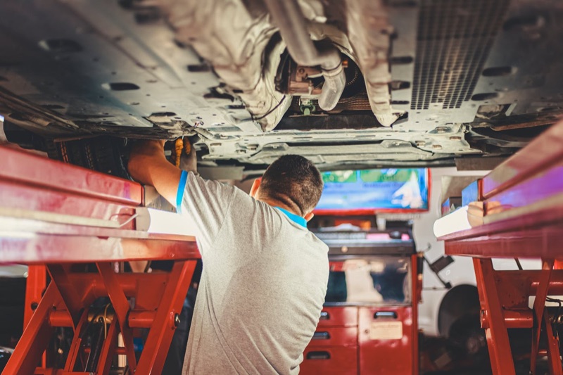 Mechaniker arbeitet unter einem Fahrzeug